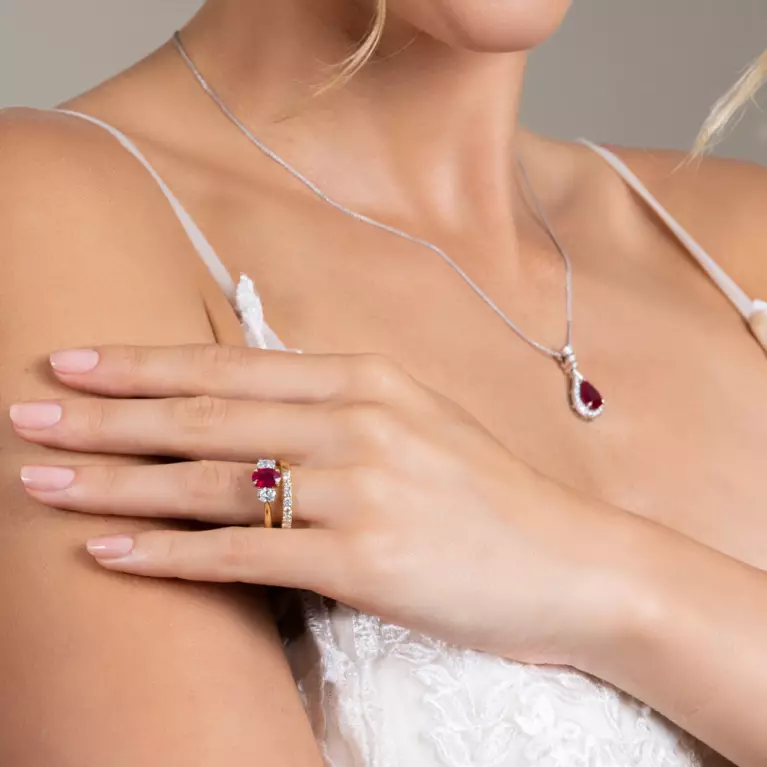 A bride wearing a yellow gold ruby and diamond ring and a ruby and diamond necklace
