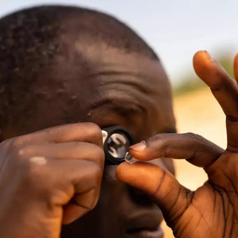 Man inspecting a diamond with a jewellery loupe
