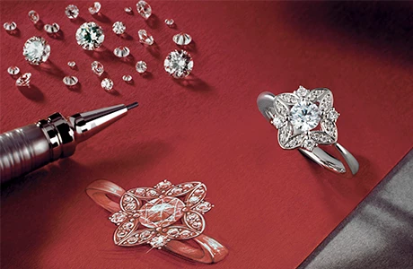 a red table topped with jewellery design drawing, a diamond ring and a pencil.	