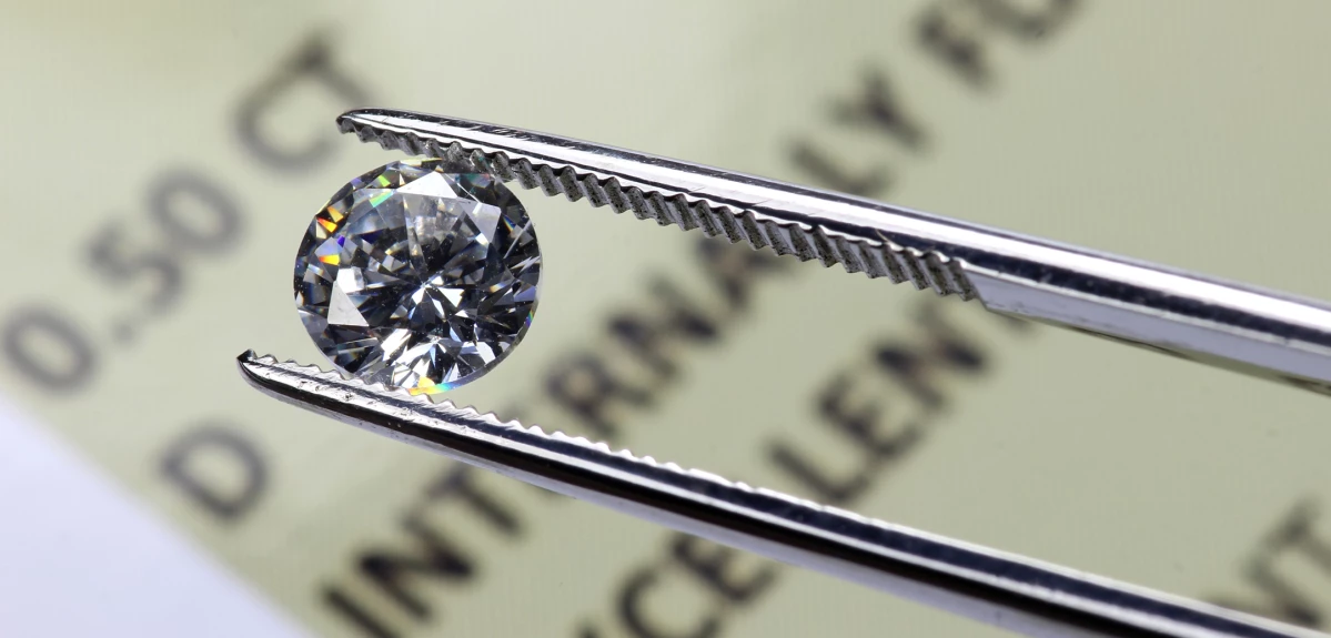Diamond in tweezers above a certificate