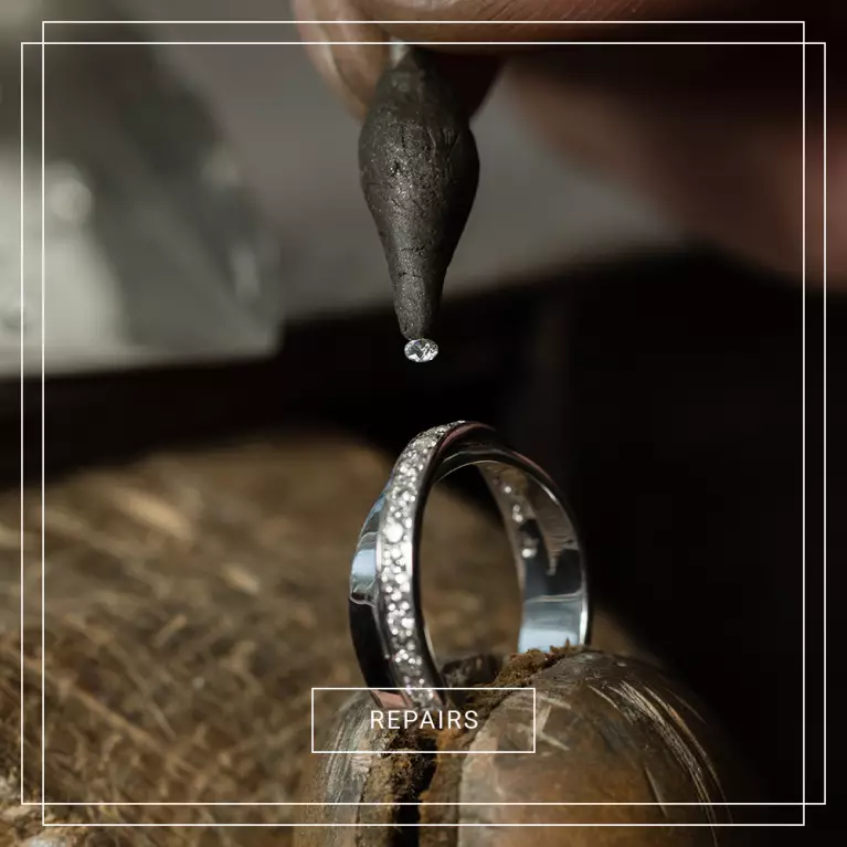 White gold diamond wedding band held in a jewellers clamp. Find out more about our repairs.